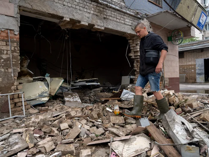 Un rezident local curăță resturile unui magazin distrus în Herson. Foto: Getty Images