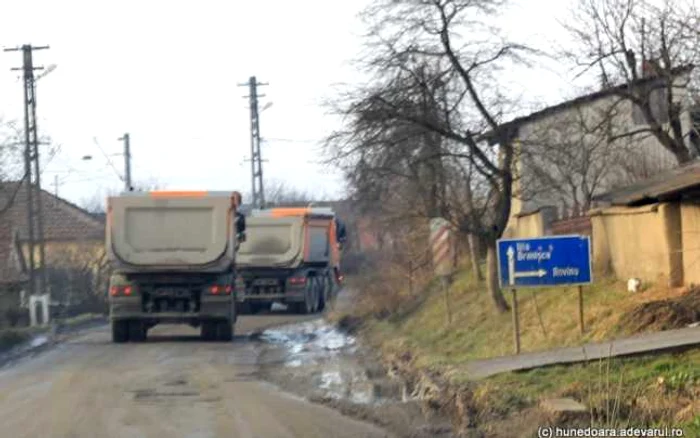 Zeci de camioane încărcate cu materiale folosite la terasamentul autostrăzii tranzitează zilnic Brănişca. FOTO: Daniel Guţă. ADEVĂRUL.