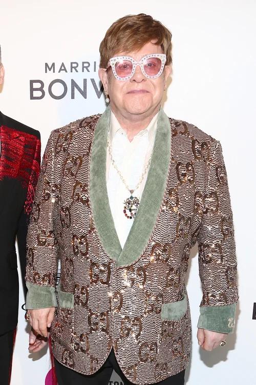 Elton John, îmbrăcat într-un sacou Gucci de culoare bej și cămașă albă