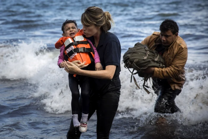 O voluntară ţine în braţe un copil sirian care a sosit cu un grup de emigranţi din Turcia pe insula grecească Lesbos FOTO AP