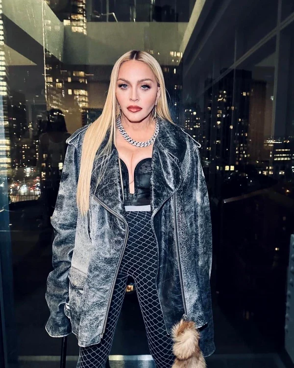 Madonna îmbrăcată în negru, pozată în fața unui geam 
