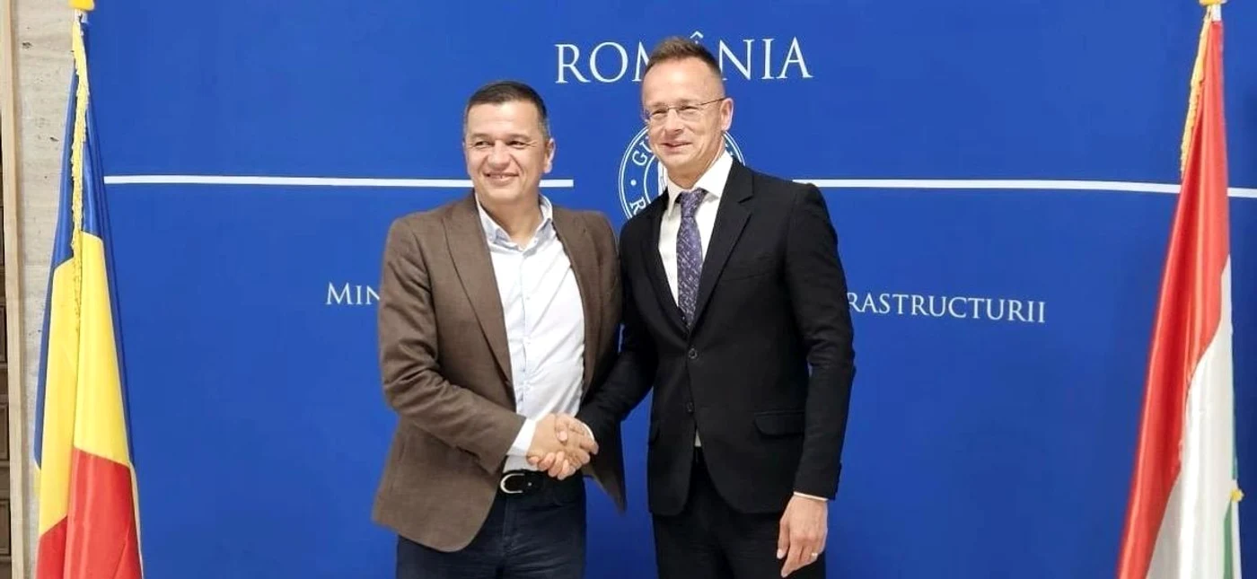 Ministrul Transporturilor, Sorin Grindeanu, și Peter Szijjarto în timp ce își strâng mâna.