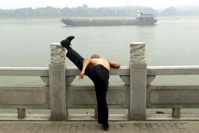 Un bărbat face exerciţii fizice pe malul râului Han, în oraşul chinez Wuhan