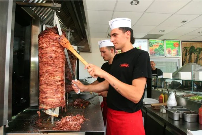 Interior shaormerie, vânzător preparând o shaorma.