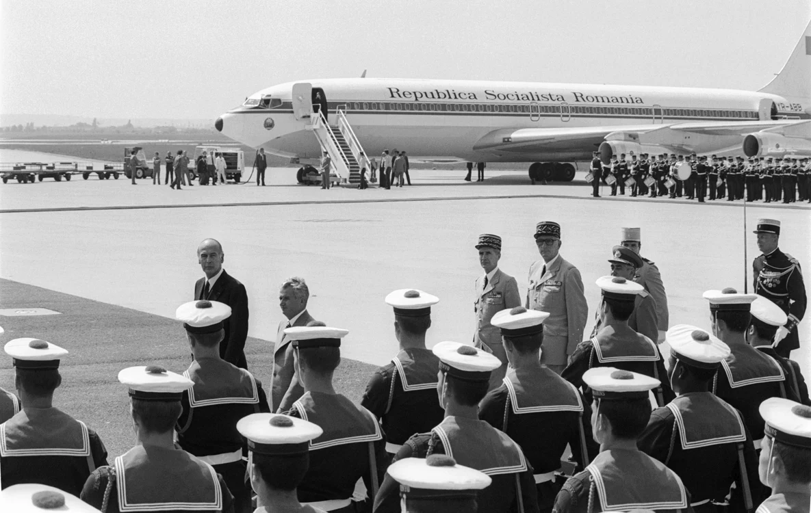 Iulie 1980, Aeroportul Orly, Paris. Preşedintele Franţei, Valery Giscard  D’Estaing, îl întâmpină pe dictatorul  comunist Nicolae Ceauşescu. Pe fundal, aeronava prezidenţială
