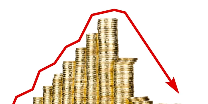 Săgeată roșie care indică scădere peste mai multe fișicuri de monede