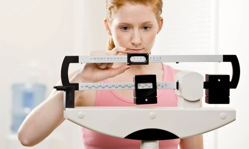 young woman weighs herself at gym jpeg