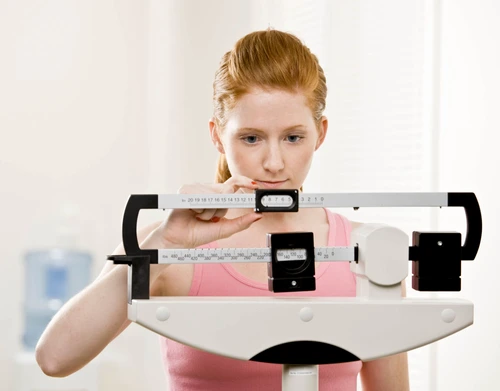 young woman weighs herself at gym jpeg