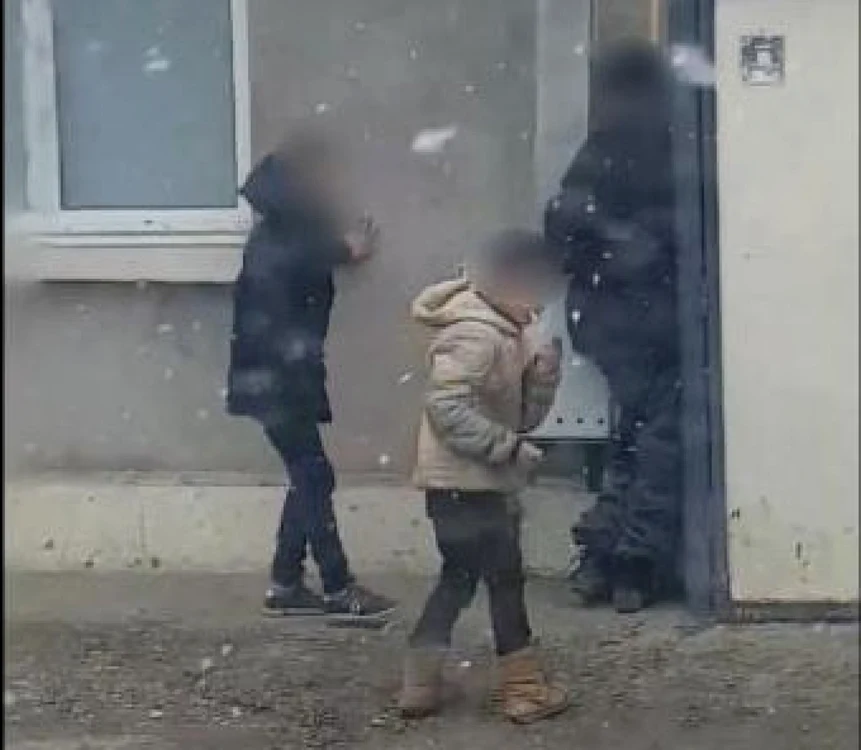 Unul dintre copii îşi aprinde o ţigară după ce a obosit lovindu-l pe omul străzii  Foto: captură video