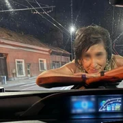 O femeie sare pe capota unei mașini și îi zâmbește șoferului, pe o stradă din Cluj