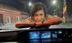 O femeie sare pe capota unei mașini și îi zâmbește șoferului, pe o stradă din Cluj