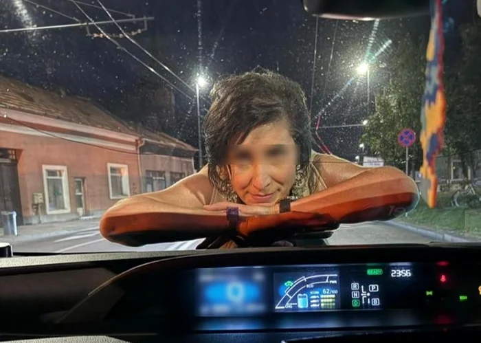 O femeie sare pe capota unei mașini și îi zâmbește șoferului, pe o stradă din Cluj