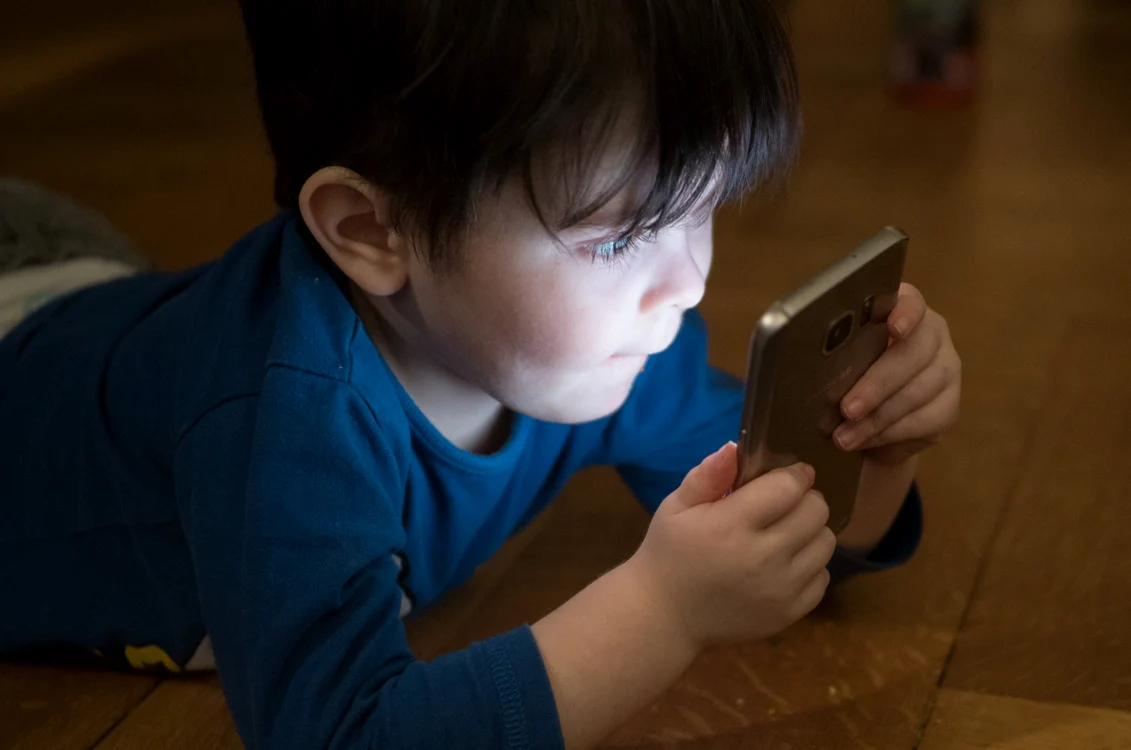 Copil privind ecranul luminat al unui telefon. Foto: Pixabay