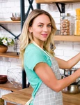 smiling woman looking camera while dusting kitchen jpg