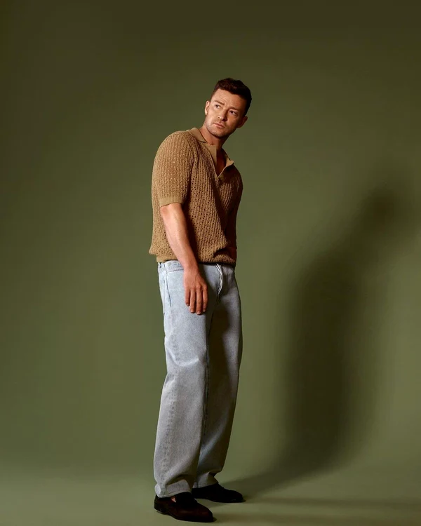 Justin Timberlake, în blugi gri și un pulover maro