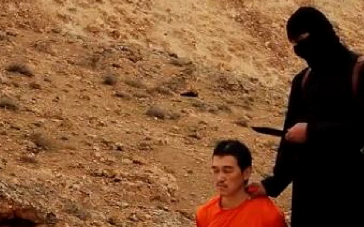 
    În imaginile publicate de ISIS, Kenji Goto apare în genunchi lângă un militant jihadistcaptură video  