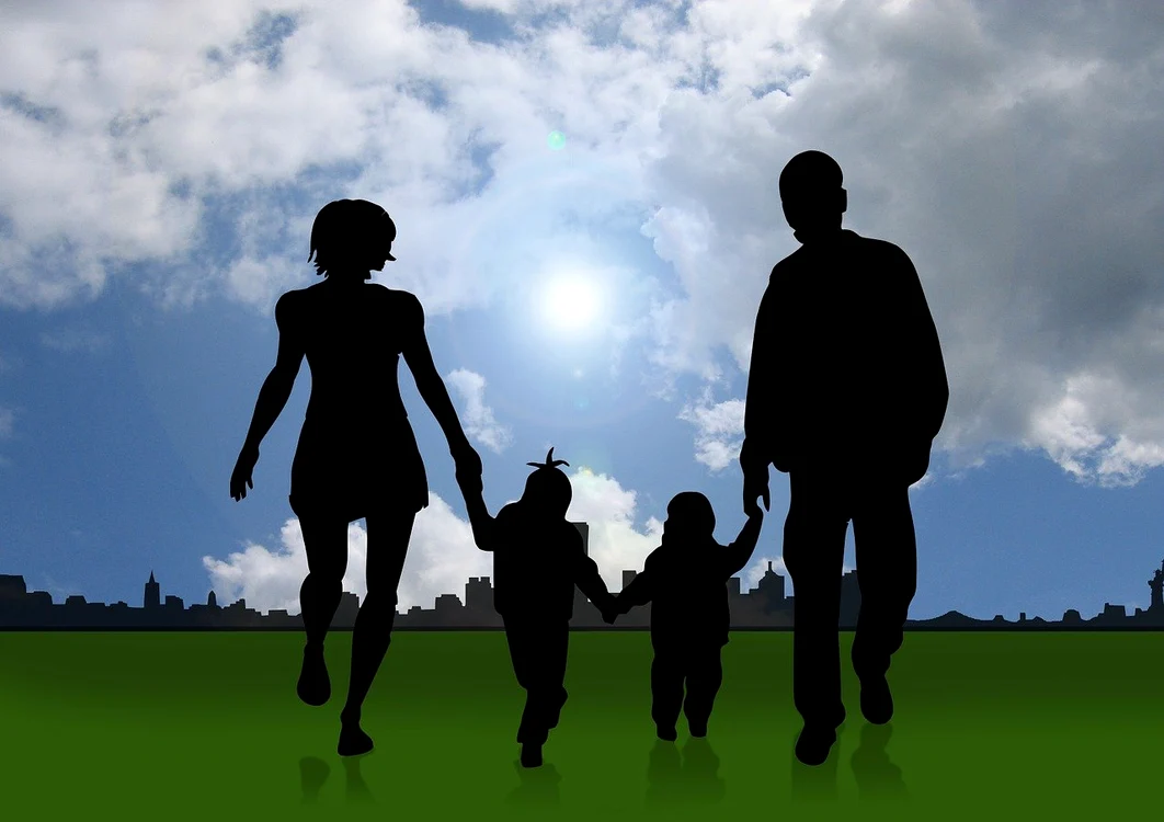 O familie cu doi copii alergând pe o pajiște la marginea orașului