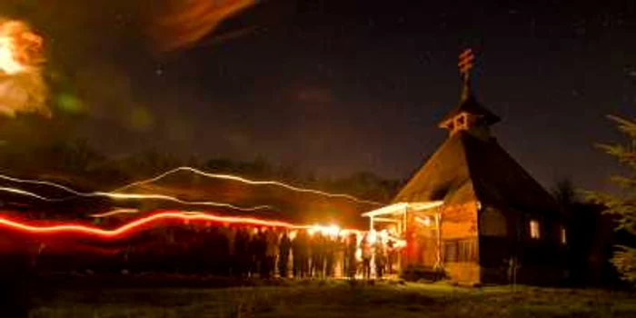 Într-o fotografie făcută cu un timp de expunere lungă oamenii merg cu lumânări aprinse în timpul serviciului religios de Paştele ortodox la o biserică din Malu Spart