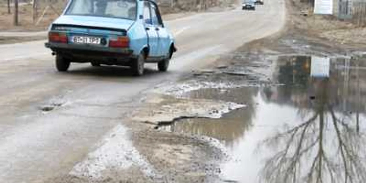 Şoferul unei Dacii este nevoit să intre pe sensul opus de mers pentru a ocoli craterul apărut în zona Pensiunii Lebăda