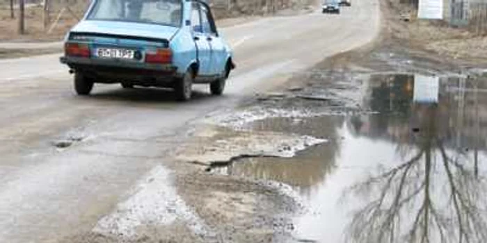 Şoferul unei Dacii este nevoit să intre pe sensul opus de mers pentru a ocoli craterul apărut în zona Pensiunii Lebăda