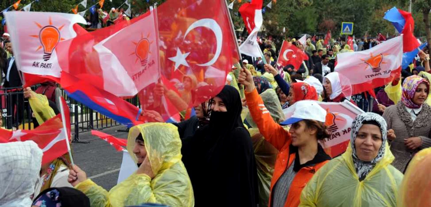 Femei care flutură steagul Turciei în timp ce-l ascultă pe Ahmet Davutoglu, premierul ţării şi liderul AKP, în timpul unei adunări în Diyarbakir, înaintea alegerilor de duminică FOTO AP