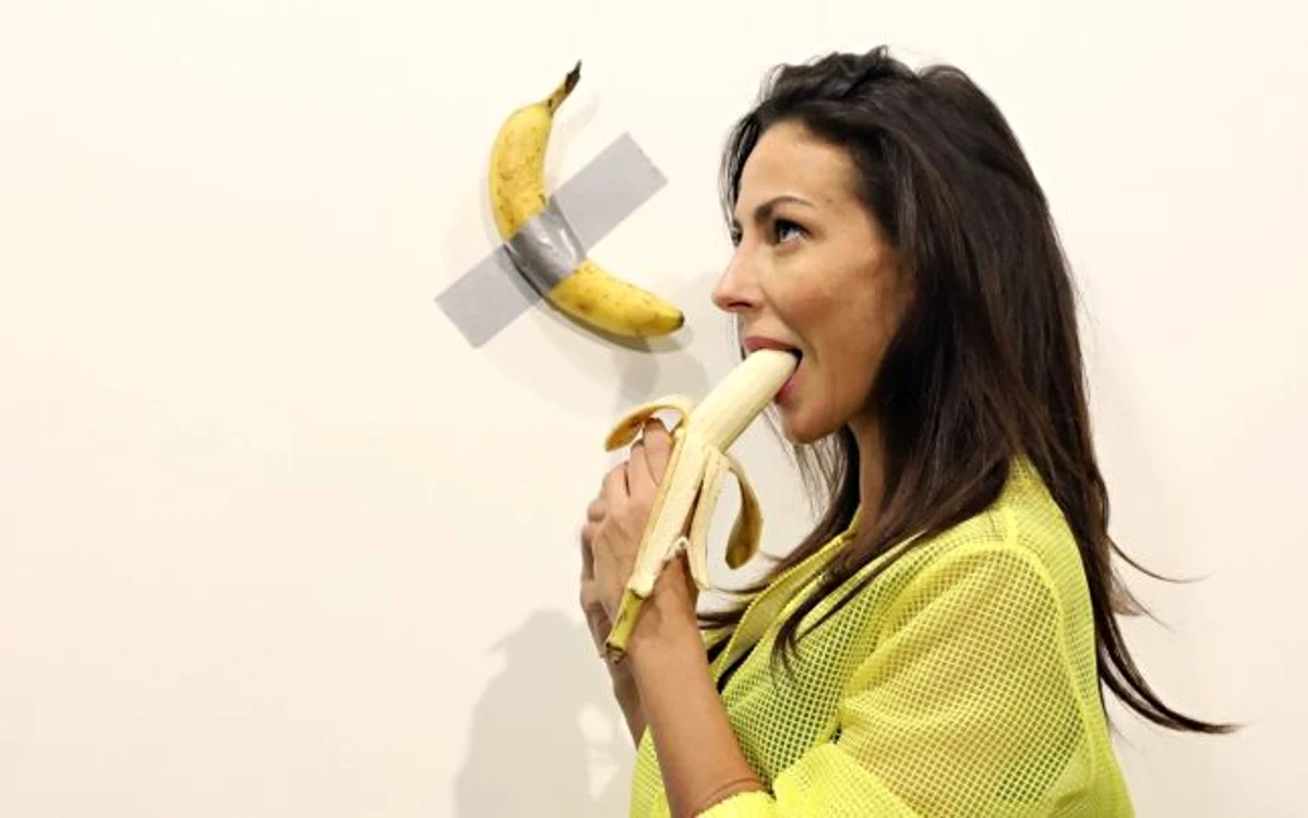 Iubitoare de artă la galeria Art Basel din Miami mănâncă o banana lângă opera de artăFOTO: Guliver/Getty Images