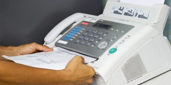 Barbat care foloseste un fax intr-un birou FOTO Shutterstock