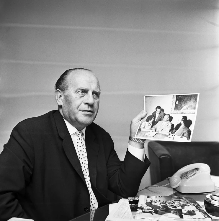 Oskkar Schindler,  în mai 1963,  prezentând ziariştilor de la United Press International fotografii din timpul ocupaţiei naziste a Cracoviei 