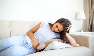 woman painful expression holding hands against belly suffering menstrual period painsitting sad home bed having tummy cramp female health concept jpg