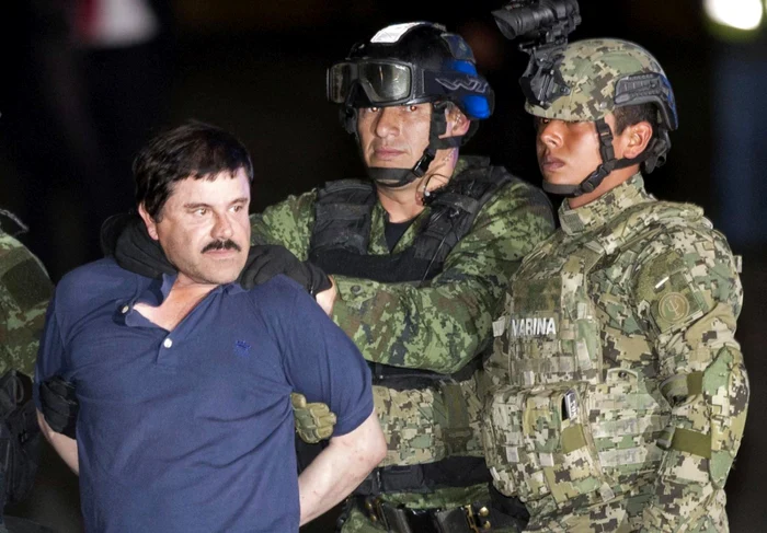 Joaquin El Chapo Guzman încătuşat e prezentat presei în timp ce e escortat spre elicopter de soldaţi mexicani lângă un hangar federal în capitala Mexicului FOTO AP