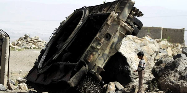 Un baiat stă langa un vehicul blindat distrus pe un drum din provincia Omran Yemen FOTO Reuters