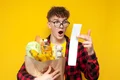 Student ținând în brațe o pungă cu diverse cumprături, fiind șocat de bonul de cumpărături  shutterstock jpg