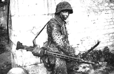 Soldat german purtând o mitralieră MG-42, pe frontul din Franța, în 1944 (© Das Bundesarchiv Bild 146-1983-109-14A)