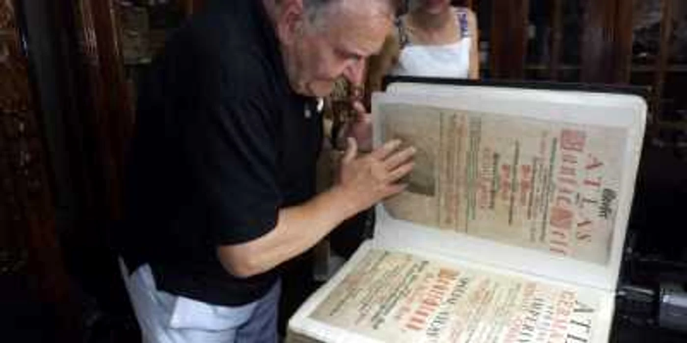 Profesorul Mircea Borcoman răsfoieşte atlasul geografic gigant de la Turnu Severin FOTO Corina Macavei