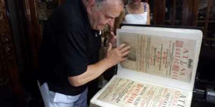 Profesorul Mircea Borcoman răsfoieşte atlasul geografic gigant de la Turnu Severin FOTO Corina Macavei