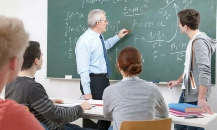 profesor dascal scrie cu creta pe tabla elev scos la tabla elevi in banci la scoala in clasa matematica jpeg