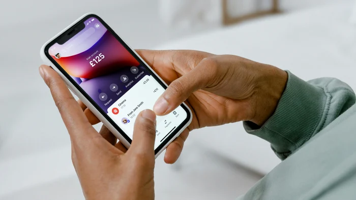Cineva tastează pe telefon numele persoanei căreia vrea să îi trimită bani
