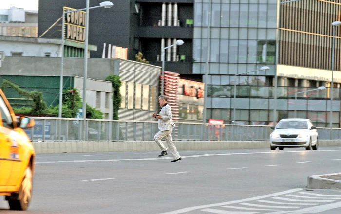 Îmbrăcat la costum și cu telefonul în mână, Becali traversează șoseaua fugind Foto: Blitz