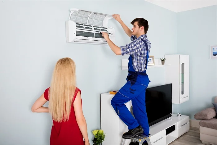 Un instalator montează un aparat de aer condiționat într-un apartament