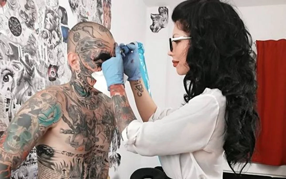 Uglyboy în timpul procedurii de acoperire a feţei cu un tatuaj realizat de Bianca Iosif