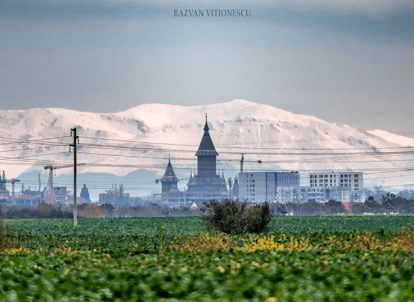 Fotografie ireală. Munții Țarcu, cu crestele înzăpezite, deasupra turlei Catedralei din Timișoara