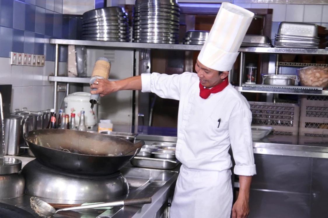 Un muncitor asiatic gatește în bucătăria unui restaurant