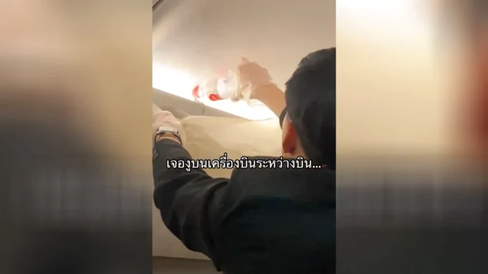 pasagerul unui avion turnând apă peste un șarpe ascuns în compartimentul pentru bagaje