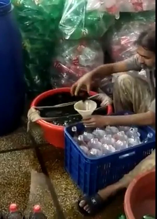 Băutura se toarnă în sticle cu etichetă Coca Cola