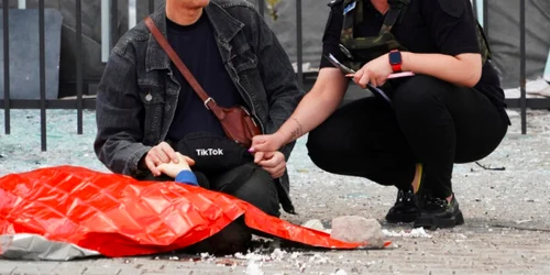 O poliţistă îl îmbărbătează pe un tată care şi-a pierdut fiul de 13 ani înm bombardamentele din Harkov FOTO Twitter 