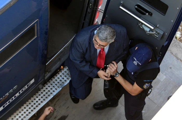 Nikos Michaloliakos escortat de un poliţist FOTO EPA-EFE