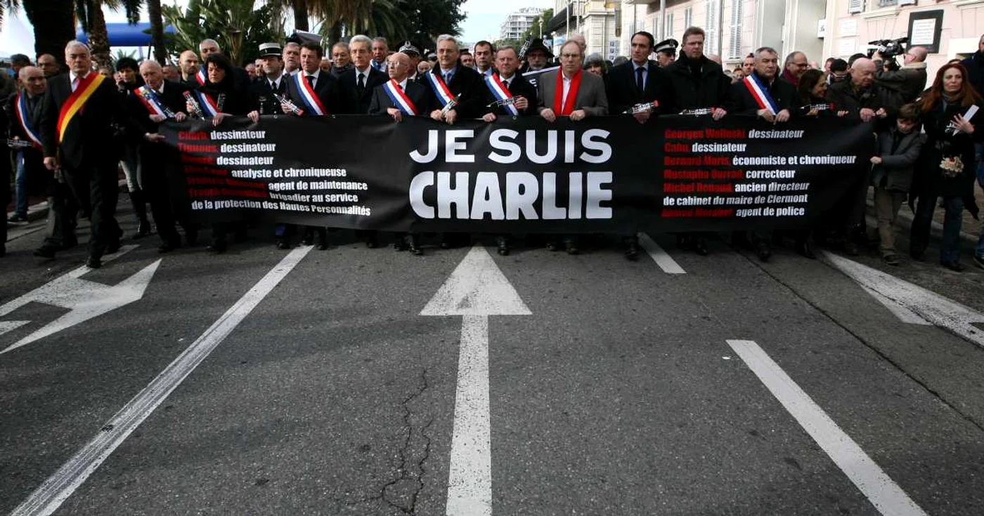 Oameni care deţin un banner pe care scrie “Eu sunt Charlie” se plimbă într-un marş tăcut pentru victimele de la ziarul satiric Charlie Hebdo