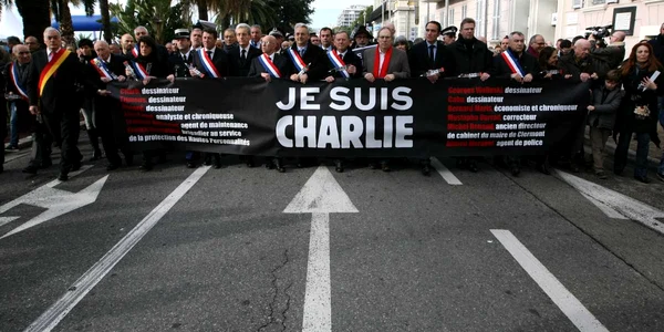 Oameni care deţin un banner pe care scrie “Eu sunt Charlie” se plimbă într-un marş tăcut pentru victimele de la ziarul satiric Charlie Hebdo