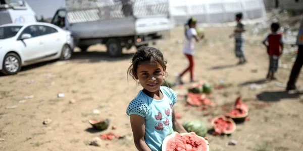 Un copil ţine un pepene într-o tabără de refugiaţi între Turcia si Siria