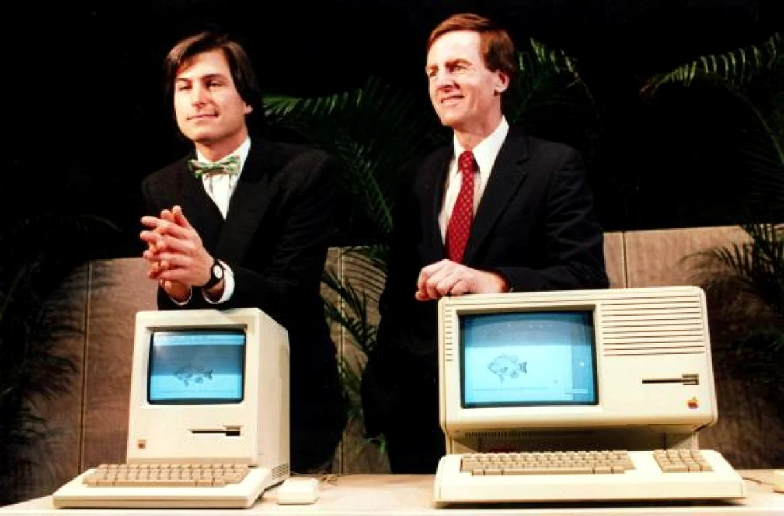 Apple Lisa (dreapta) şi Apple Macintosh în partea stângă, sub un Steve Jobs mai tânăr